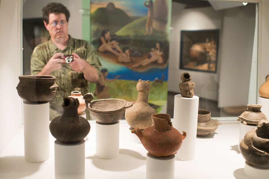 A man takes a picture of ceramic effigy art