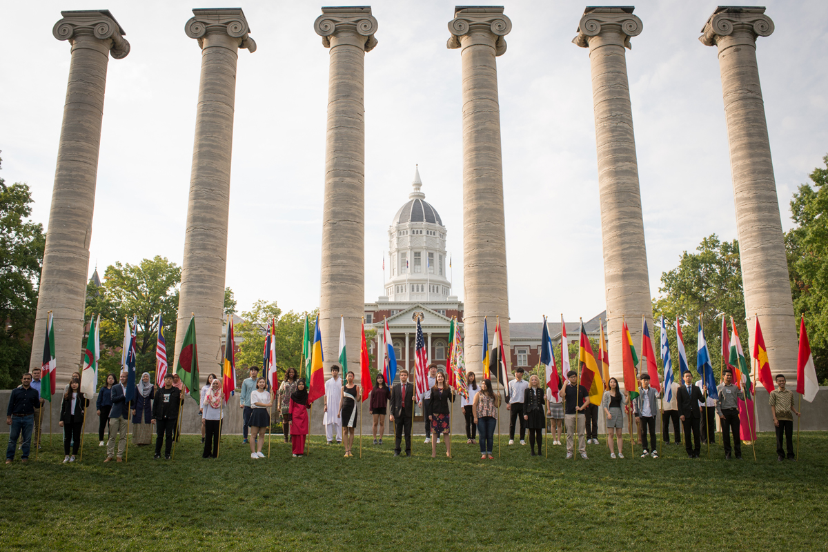 Students hold international flags in front of the Columns.