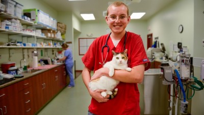 Student holding a cat in a lab