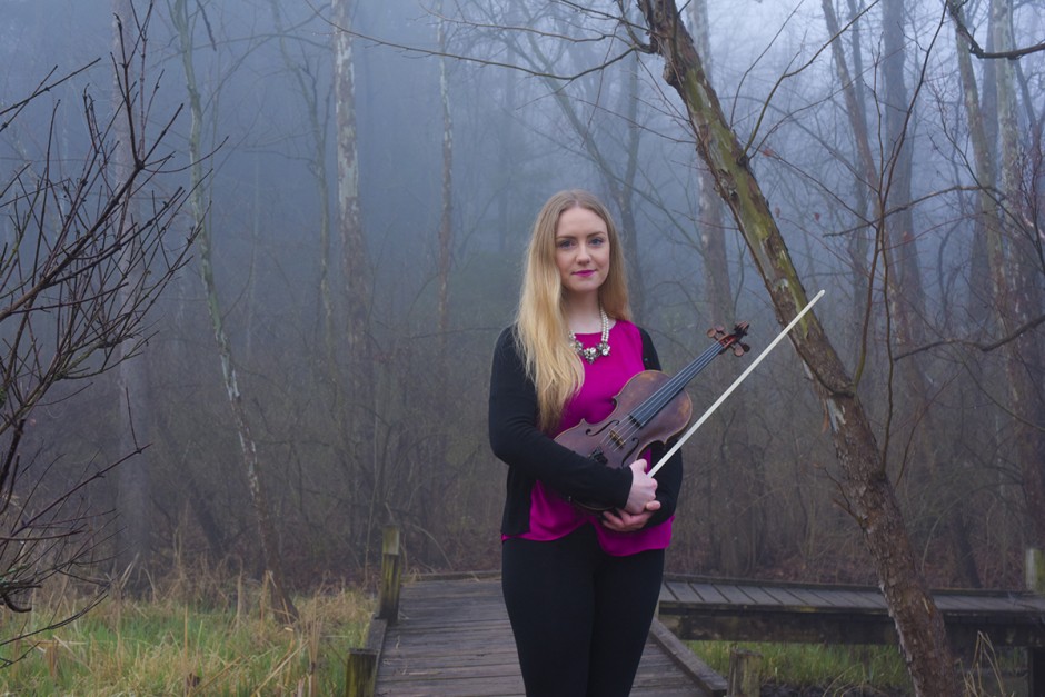 Eimear Arkins holding a viola and standing in the fog.