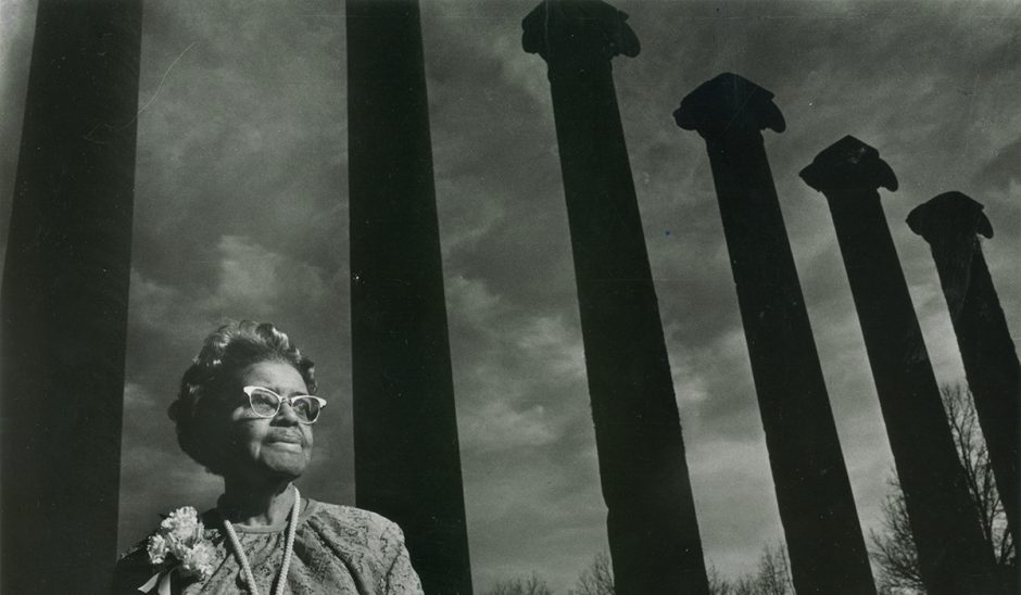 In a black and white photo, Lucille Bluford stands in front of The Columns
