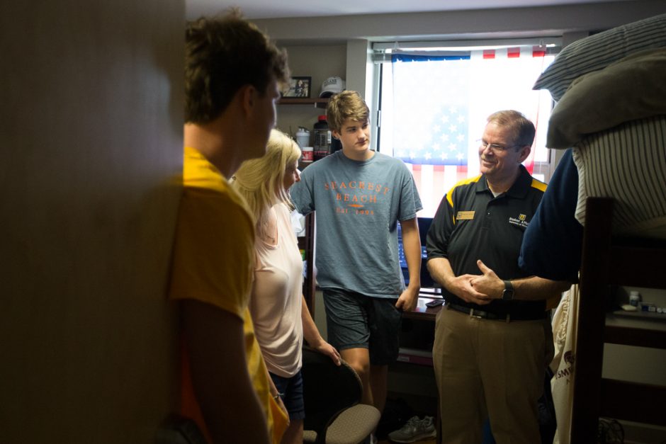 Chancellor Cartwright standing in a student's room and talking with a freshman student and his family.