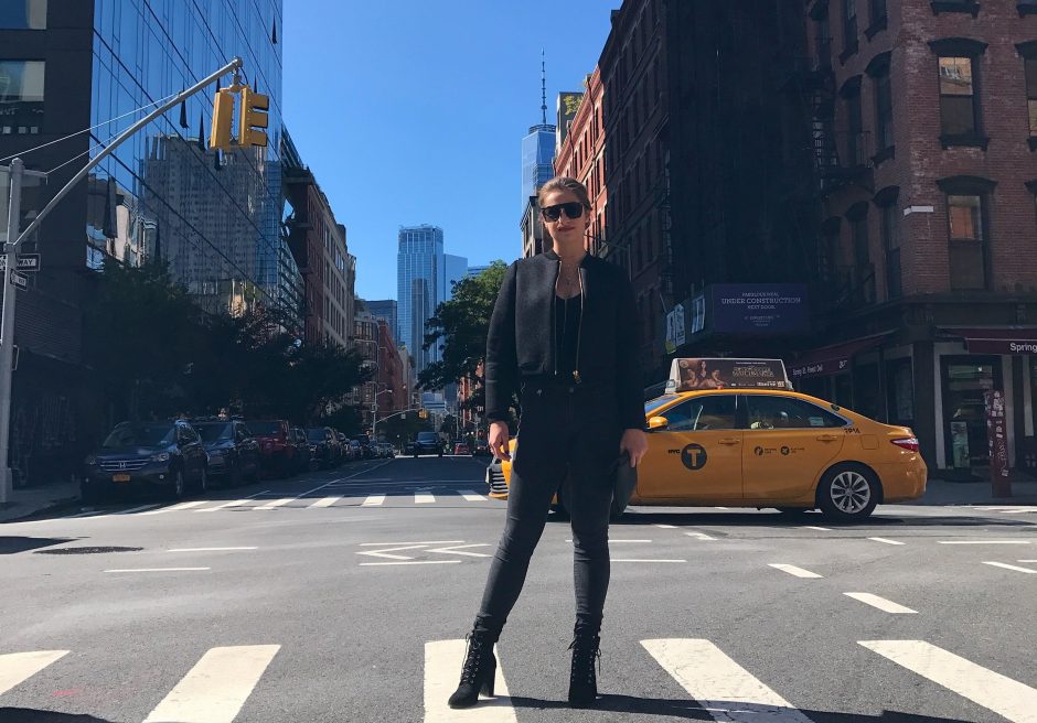This is a picture of Mackenzie Mattix standing in a NYC intersection with the NYC skyline visible in the background