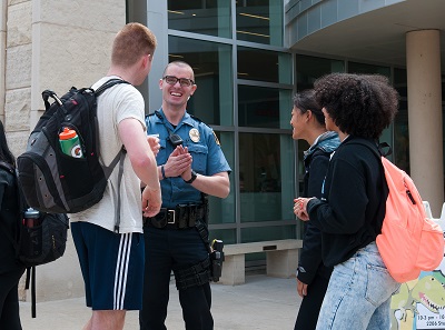 On a sunny afternoon in April, MUPD Officer Mitchel Smith talks with students, from left, Jared Holm, Emma Stetzenmeyer and Kennedi Keyes, as they wait outside the MU Student Center for a free lunch of hot dogs, hamburgers and potato chips. Interacting with students is a big part of Smith’s job, which also involves developing campus partnerships and solving problems.