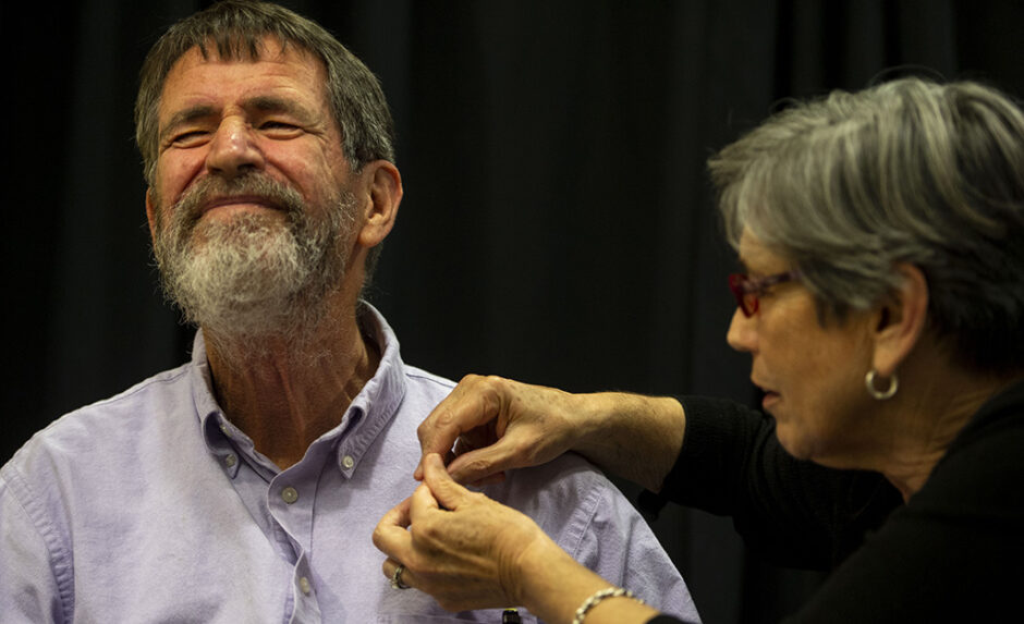 Dr. Marjorie Sable pins a pin to Dr. George Smith's shirt