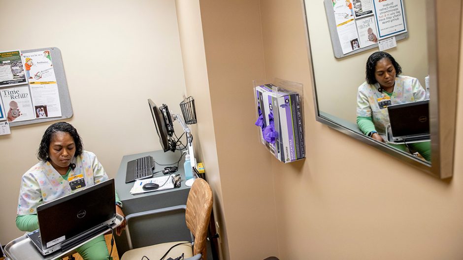 Barbara Thomas, a licensed practical nurse with the Student Health Center uses two computers to meet with patients remotely.