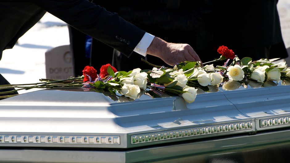person laying flowers on a casket