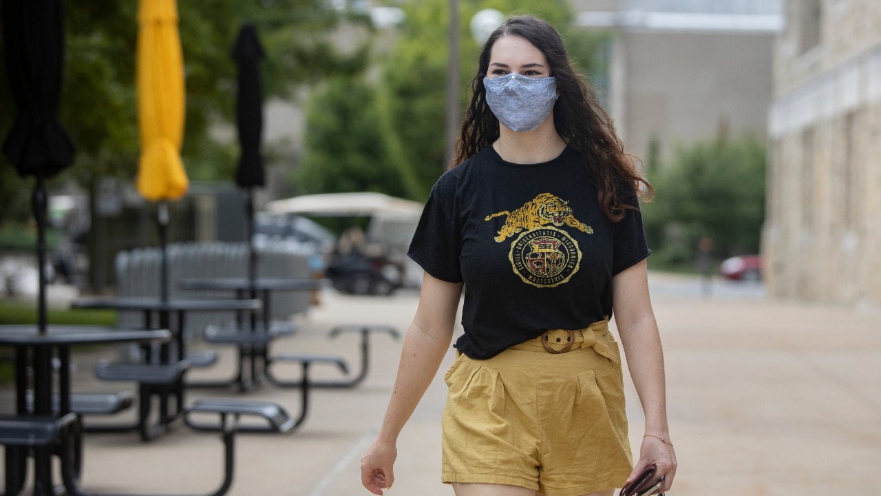 This is an image of a student walking outside of the student center with a mask.
