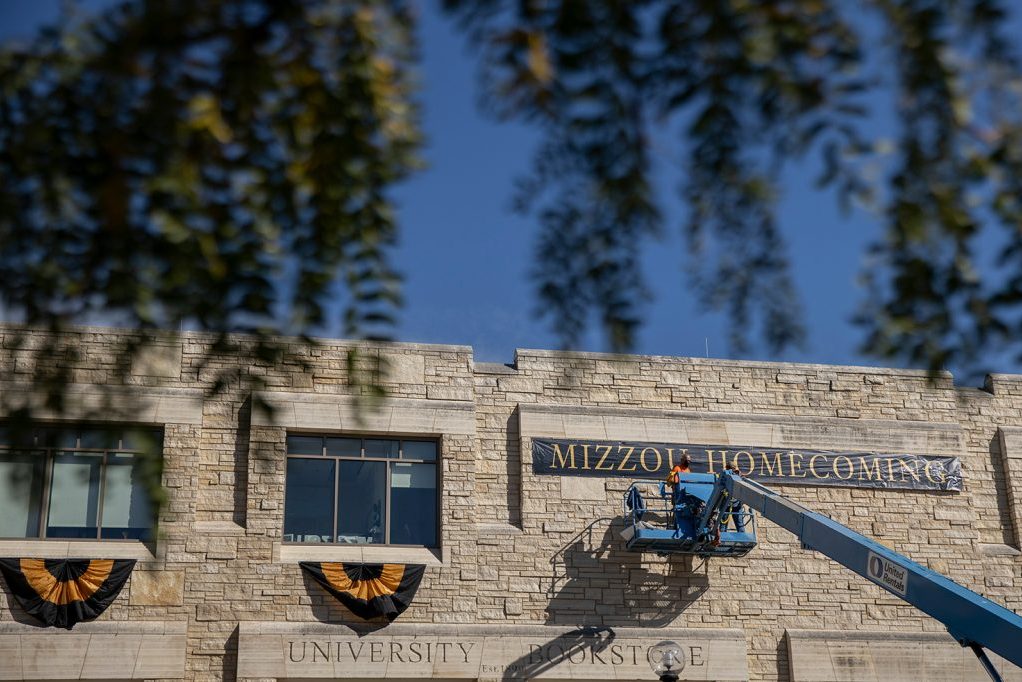 Campus facilities staff members install homecoming decorations at the Student Center.