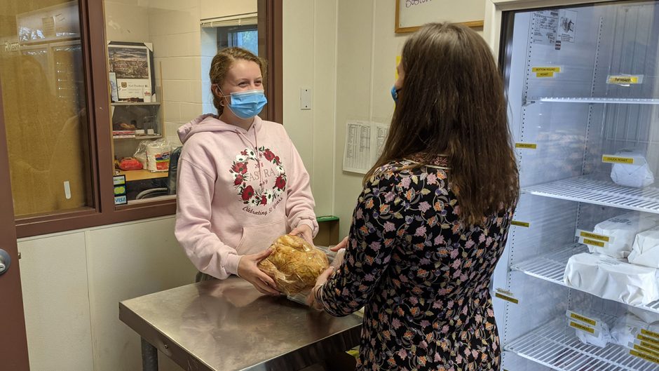 a student employee hands a client a packaged turkey