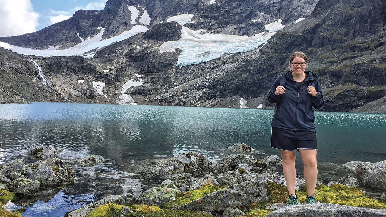 woman posing by lake and glacier