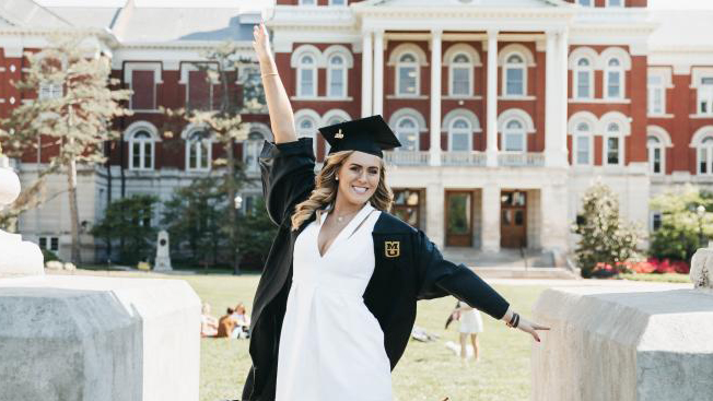 woman in cap and gown in front of the columns