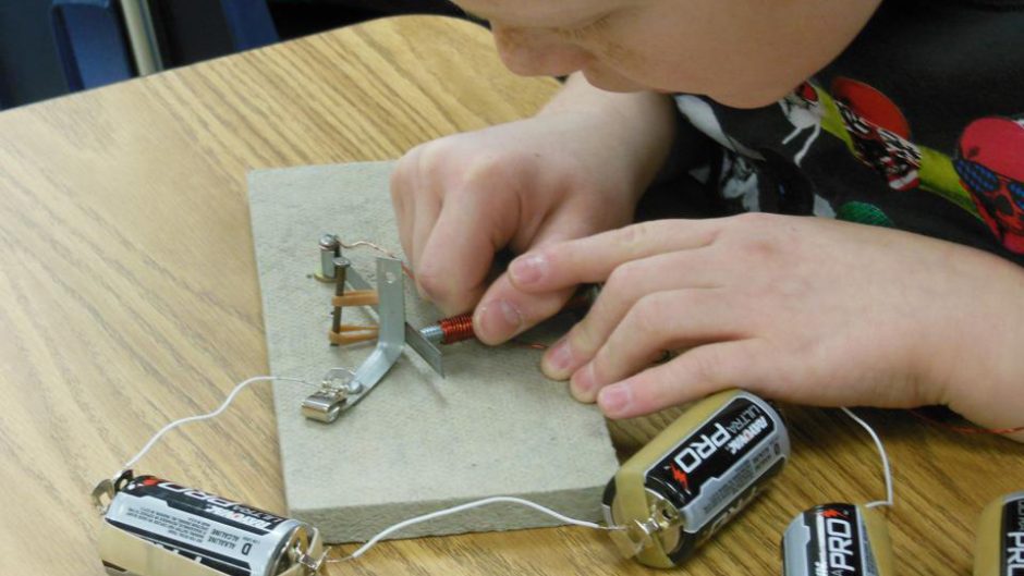 photo of a student working with batteries and tools