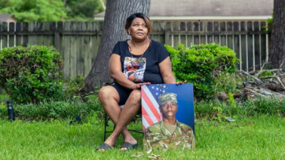 a woman poses for a portrait with a photo of her son