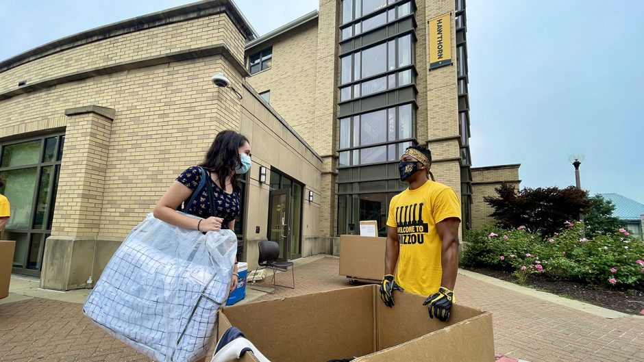a woman and a man stand outside hawthorn dorm, moving in