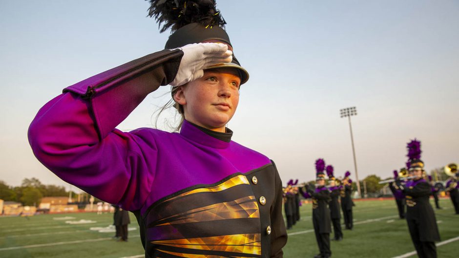 a student in a marching uniform salutes