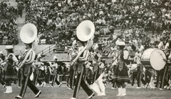 black and white photo from the 80s of a marching band playing on faurot field