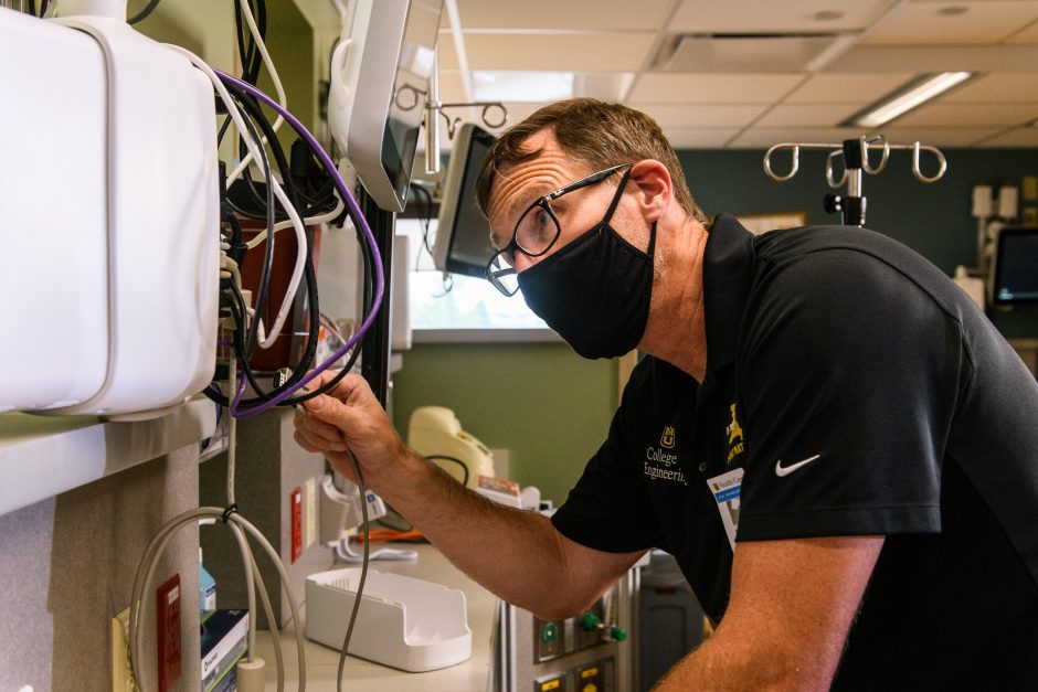 Roger Fales adjusts wires connected to a computer in the NICU