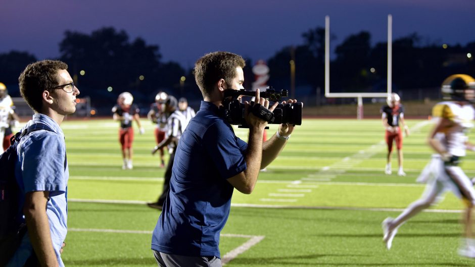 a student records video during a football game