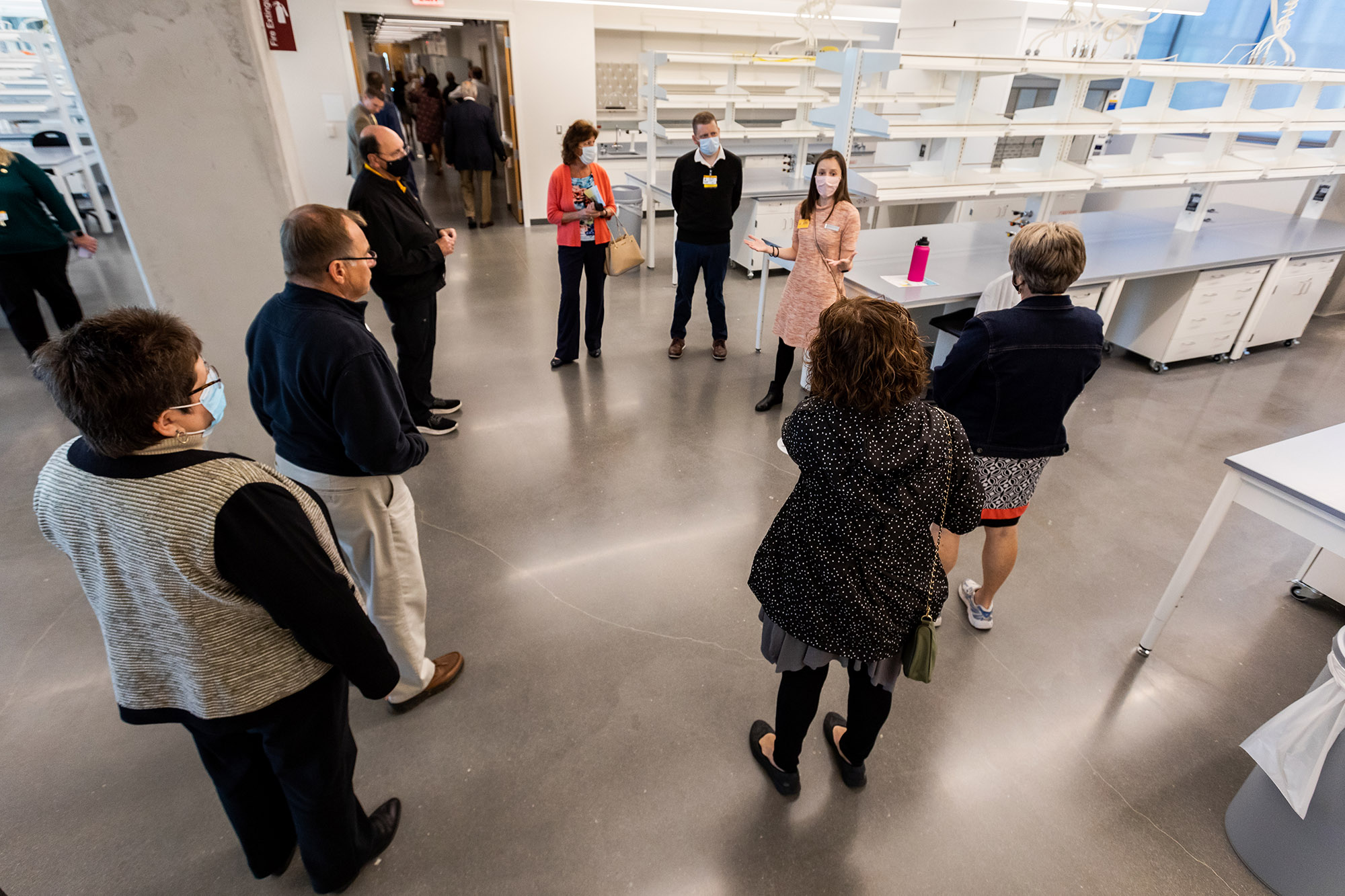 a woman gives a tour of a lab space to a group of guests