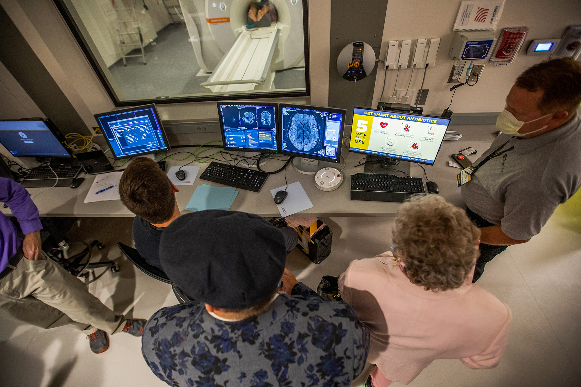 people gathered around computers and looking through the glass at someone going into the 7T MRI