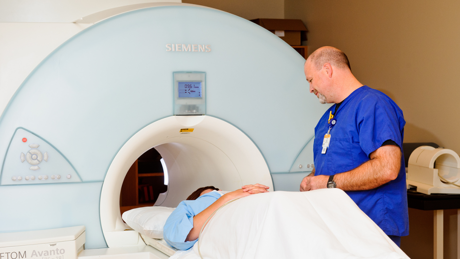 This is an image of a medical worker talking with a patient in an MRI machine