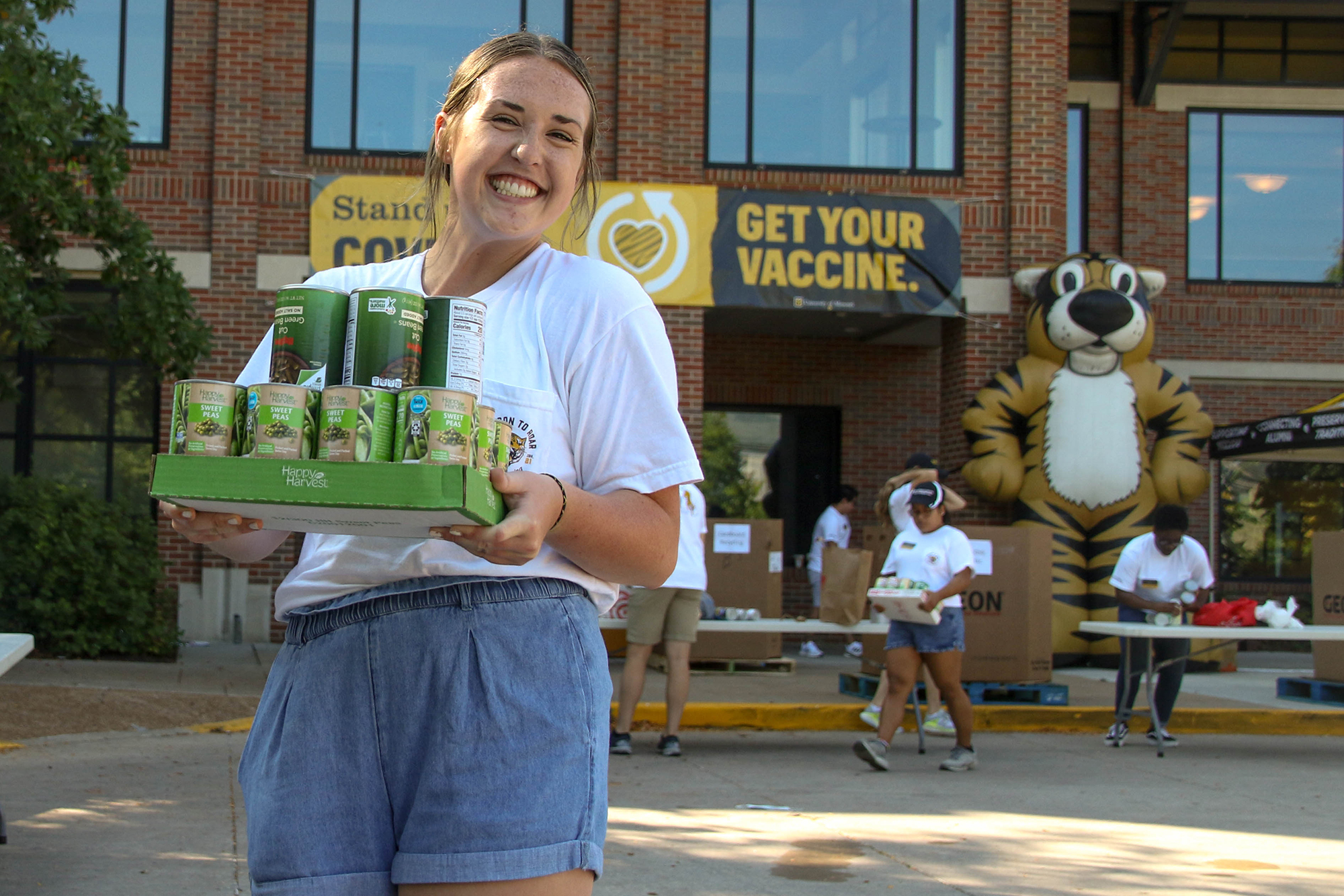 a smiling student carries food donations