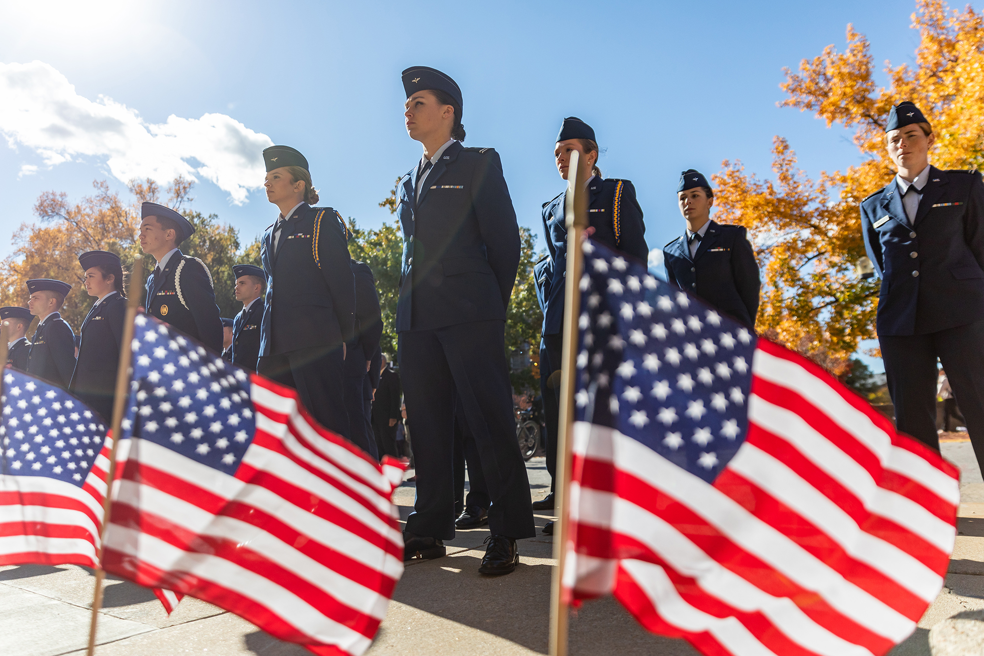 photo of rotc cadets and midshipmen with american flags in the foreground