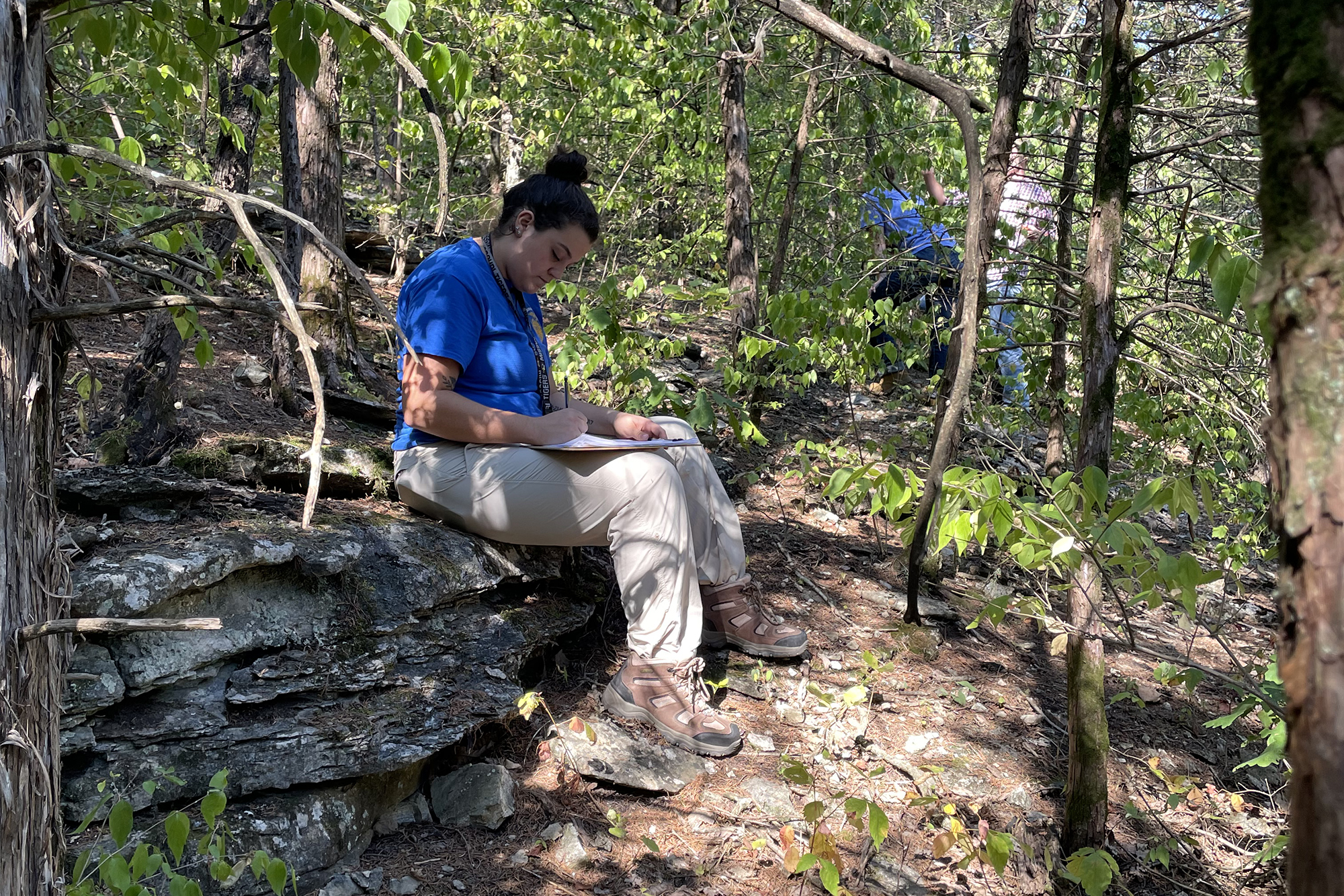 a woman takes notes while in a forest