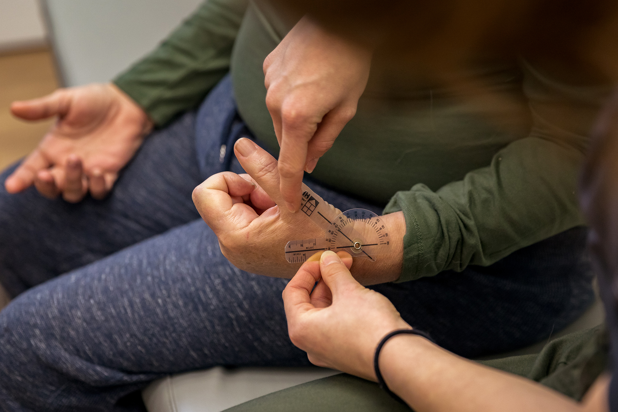 a student uses a measuring tool on cheryl overstreet's hand during a therapy session