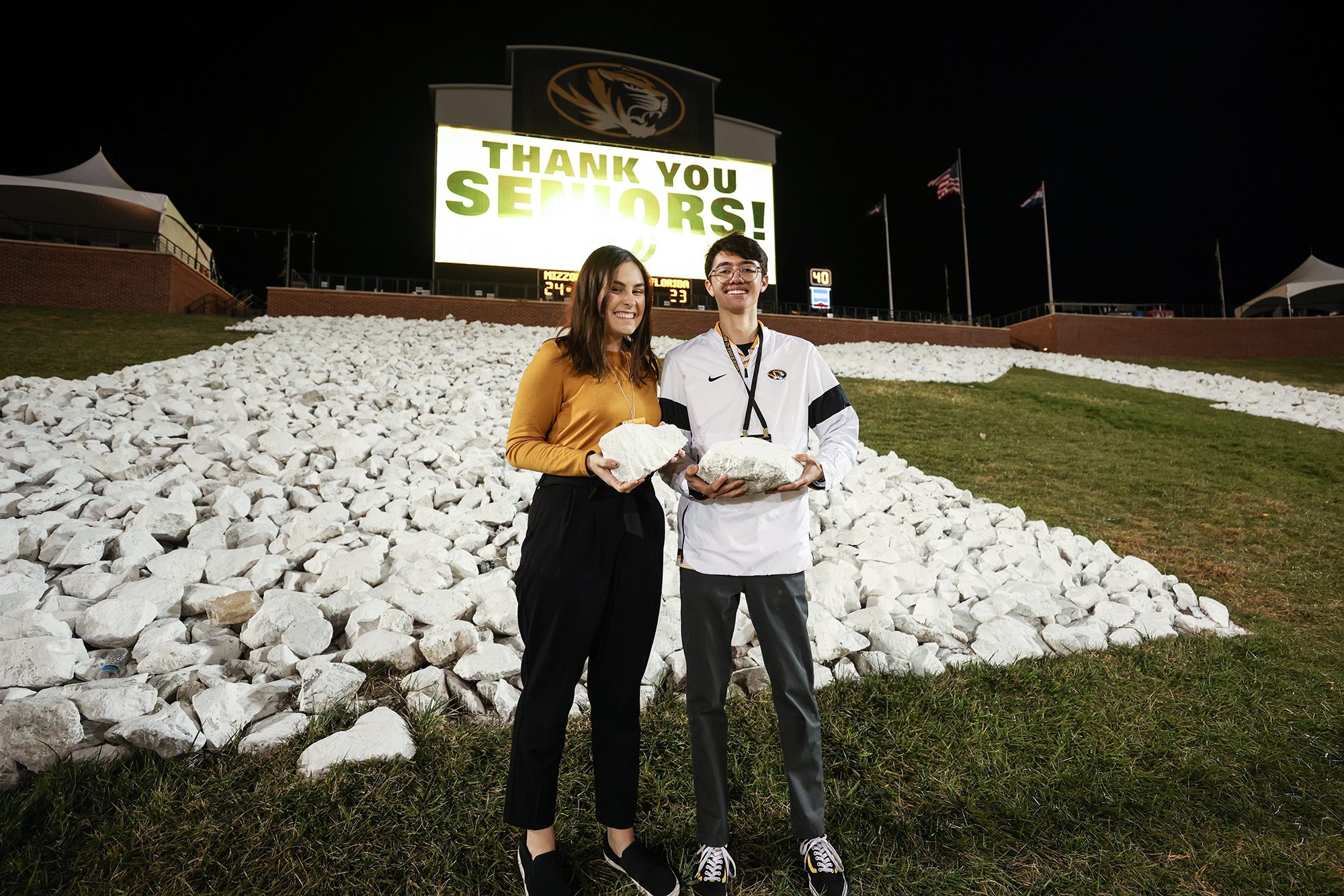 ben ramirez and friend hold a rock at faurot field on senior night