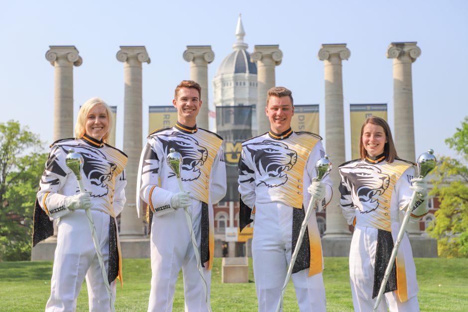 Picture of the four Marching Mizzou drum majors in their band uniforms in front of the University of Missouri columns