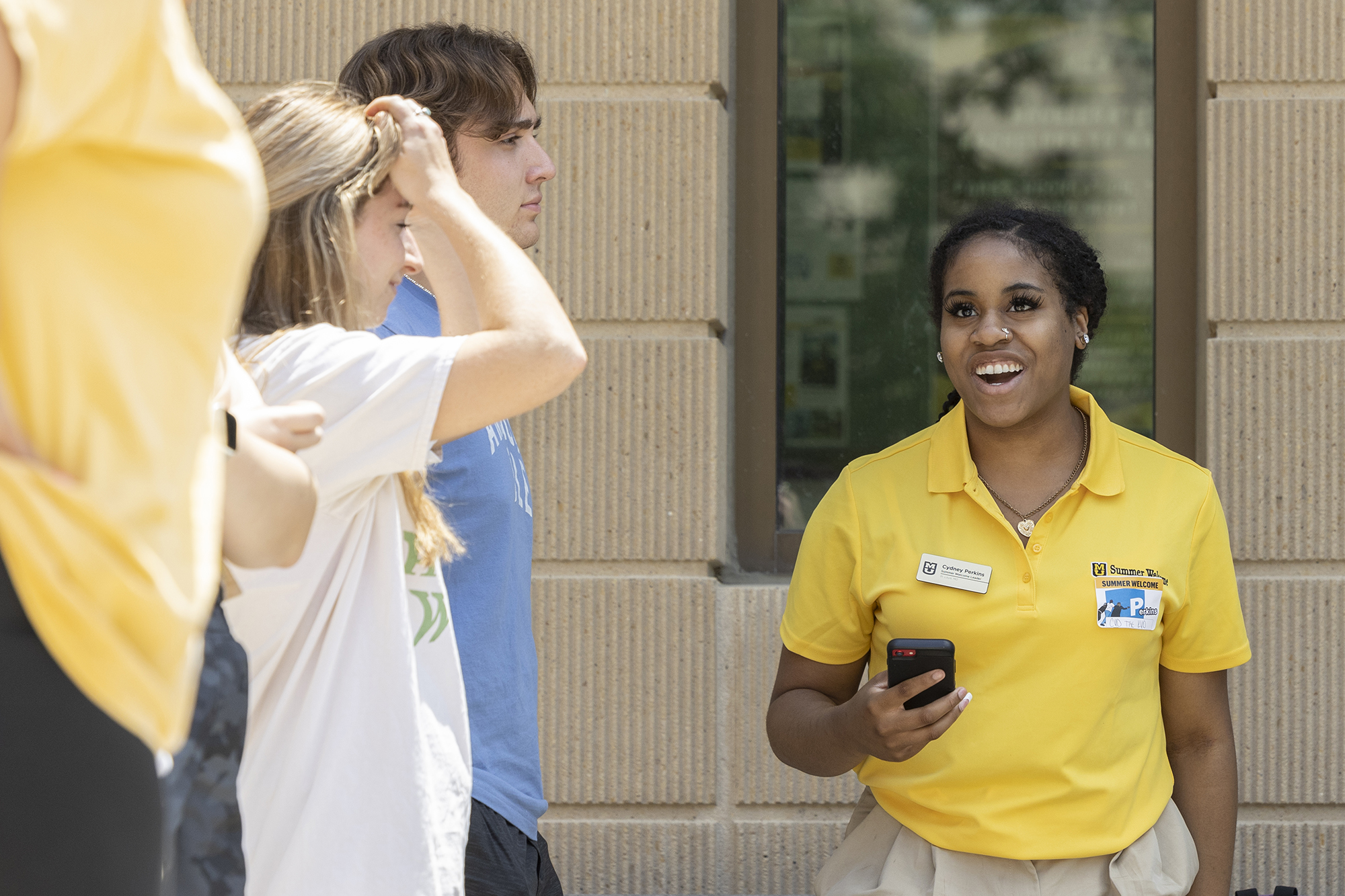 a closeup of a summer welcome leader with new students, smiling