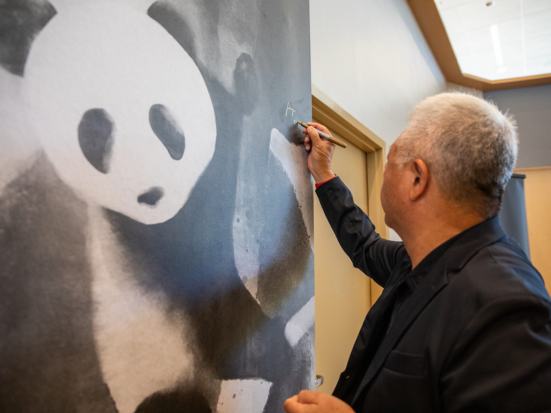 Andrew Cherng signs a wall mural