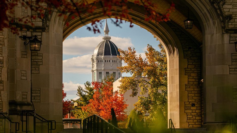 a fall photo of campus looking at jesse hall through the memorial archway