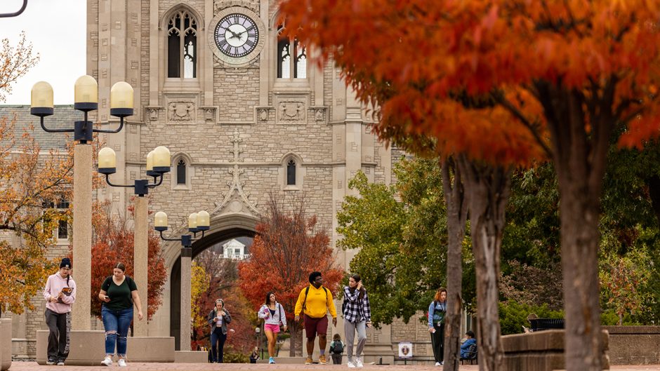 people walk to class in front of memorial union. fall trees are around.