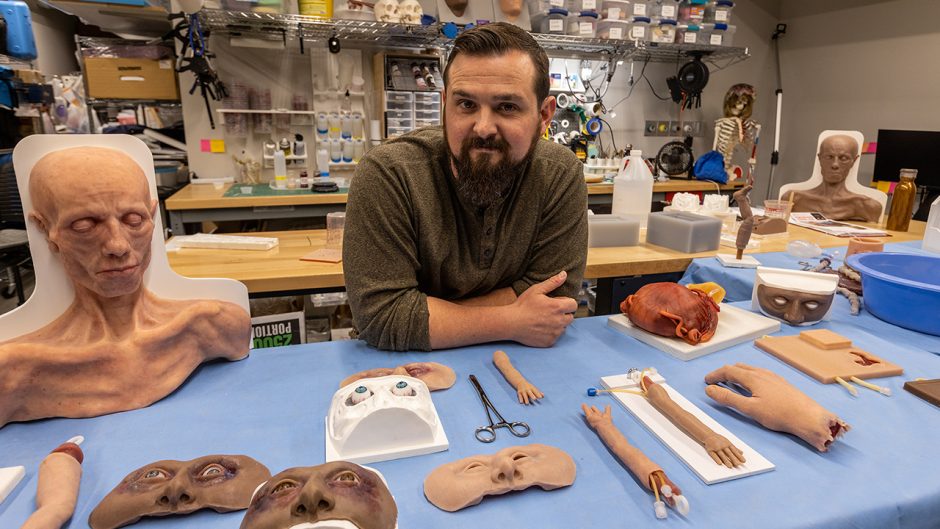 damon coyle poses with some of his trainers — lifelike body parts he creates for medical training