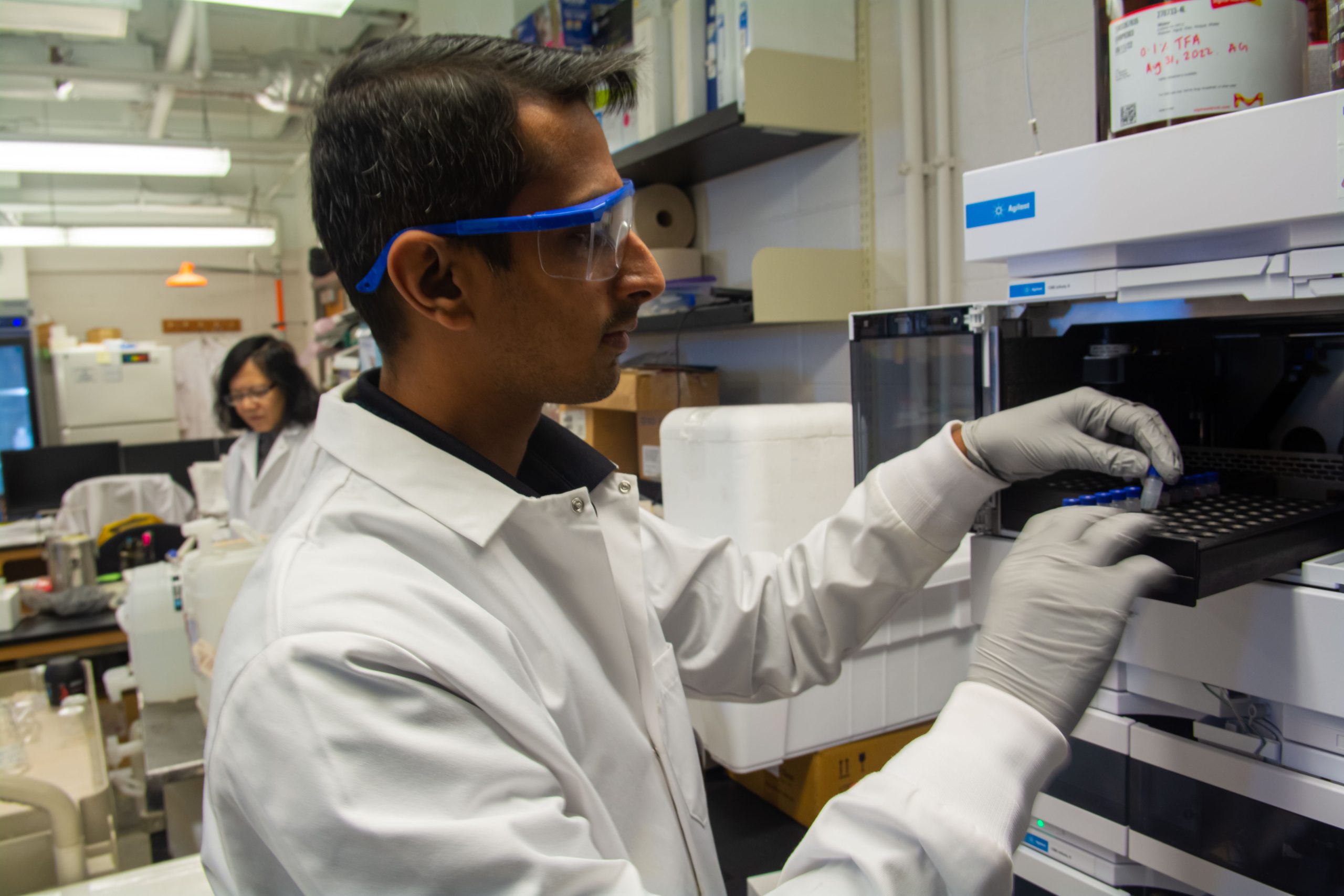 A researcher loads a test tube into a machine in a scientific lab