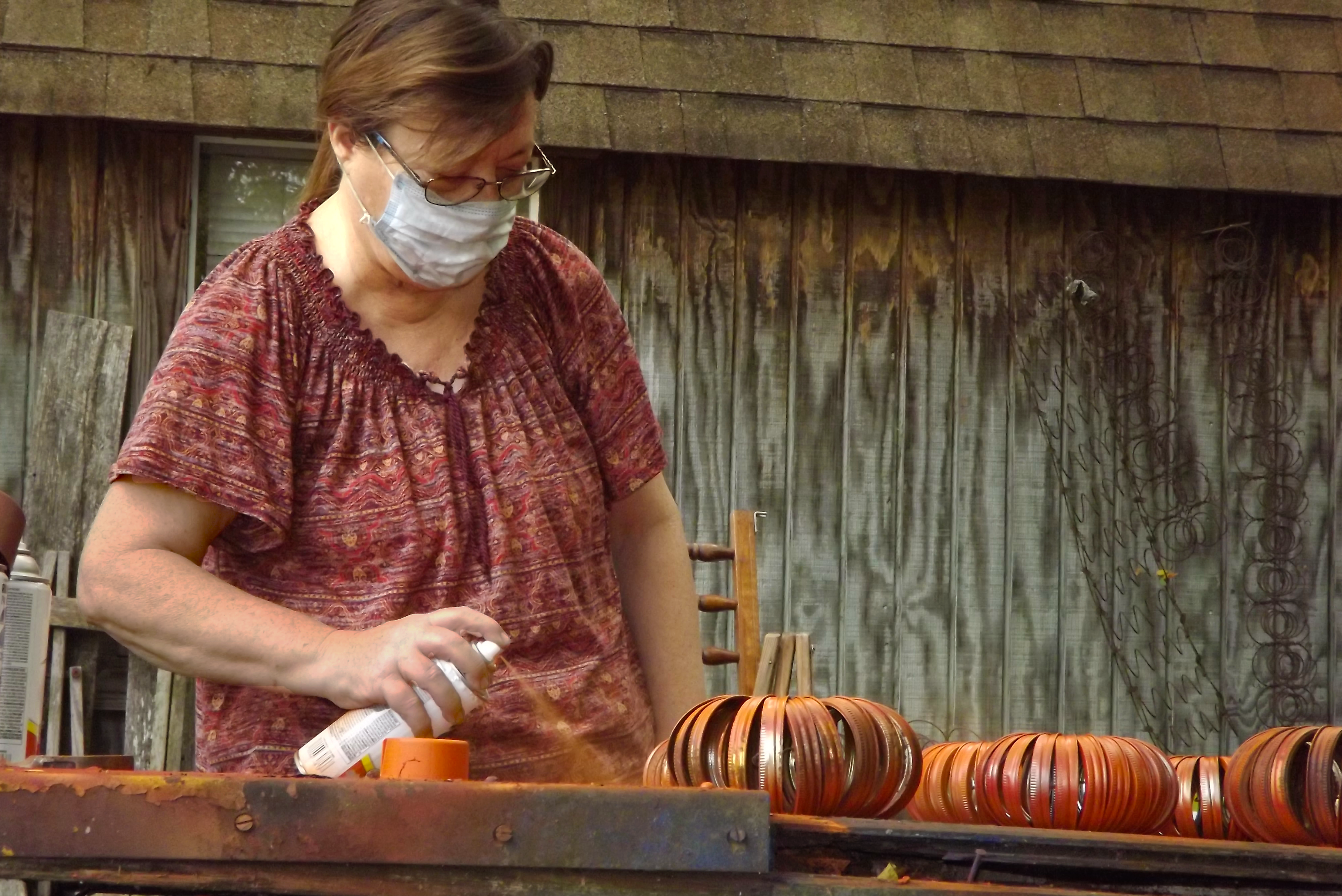 woman applies spray to orange metal shaped like pumpkins