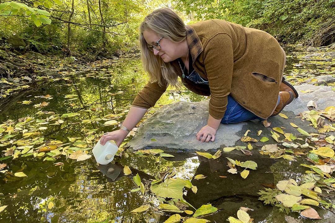 Crystal Rein collects a water sample from Columbia's Flat Branch Creek.