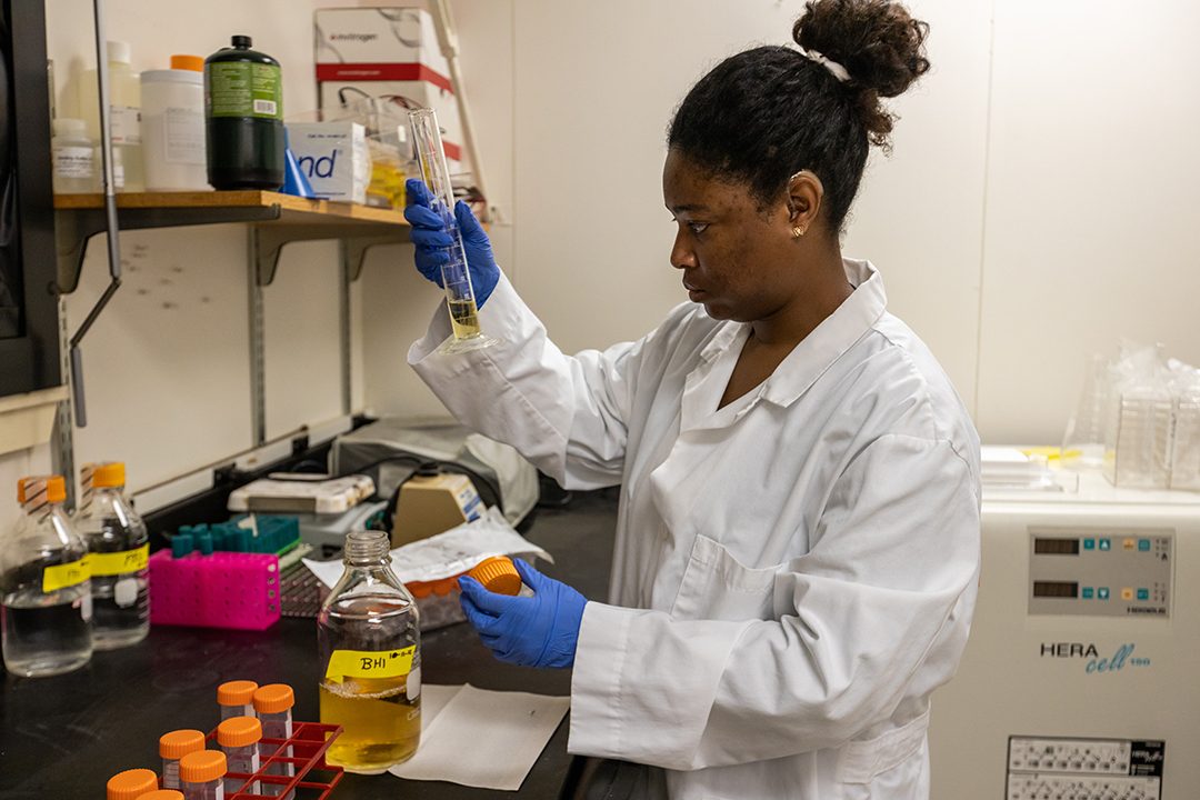 Katherine Meiser, in laboratory, measures yellow liquid in graduated cylinder.