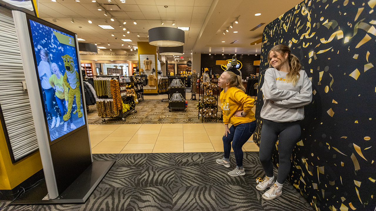 two students use the hero mirror in the mizzou store