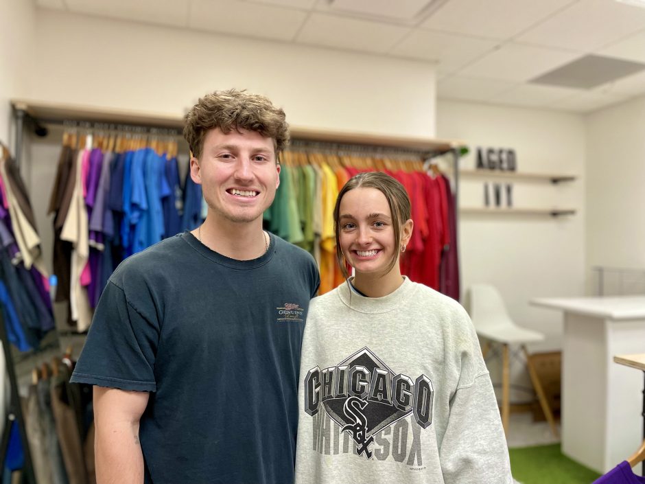 two students pose in their clothing shop