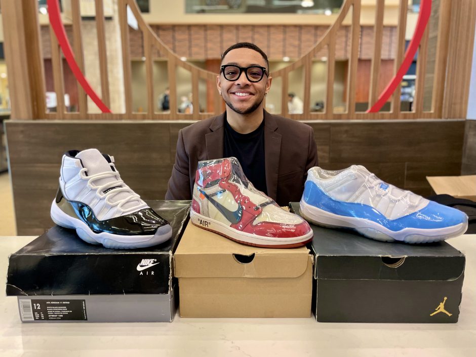 a man sits behind three pairs of nice shoes