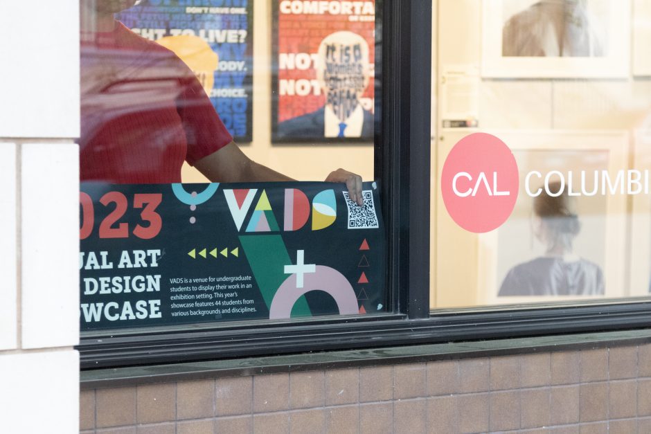 A person putting up a sign for VADS in a window.