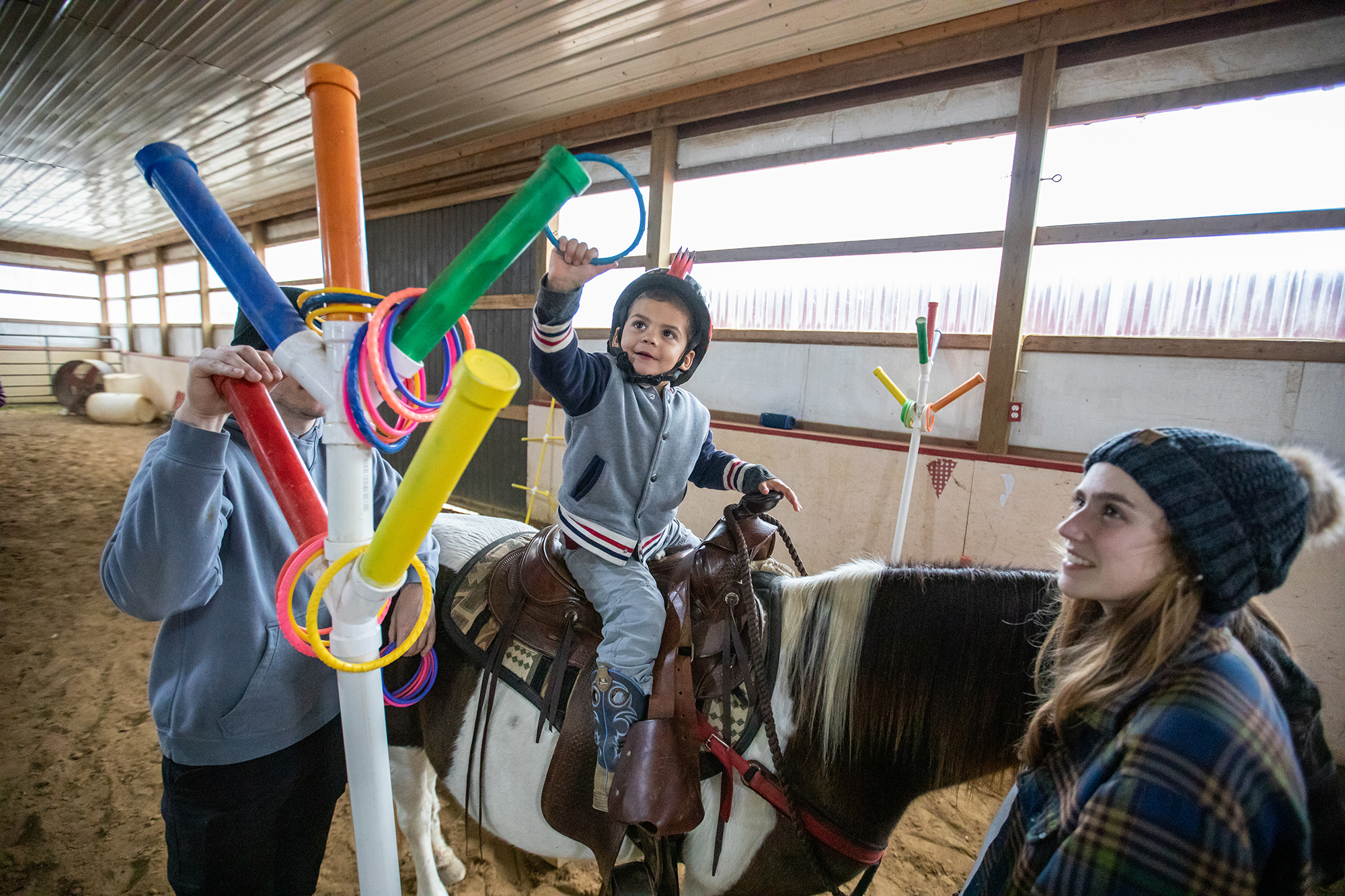 Little boy on horseback places rings on stand