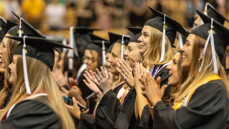 graduates clap during commencement
