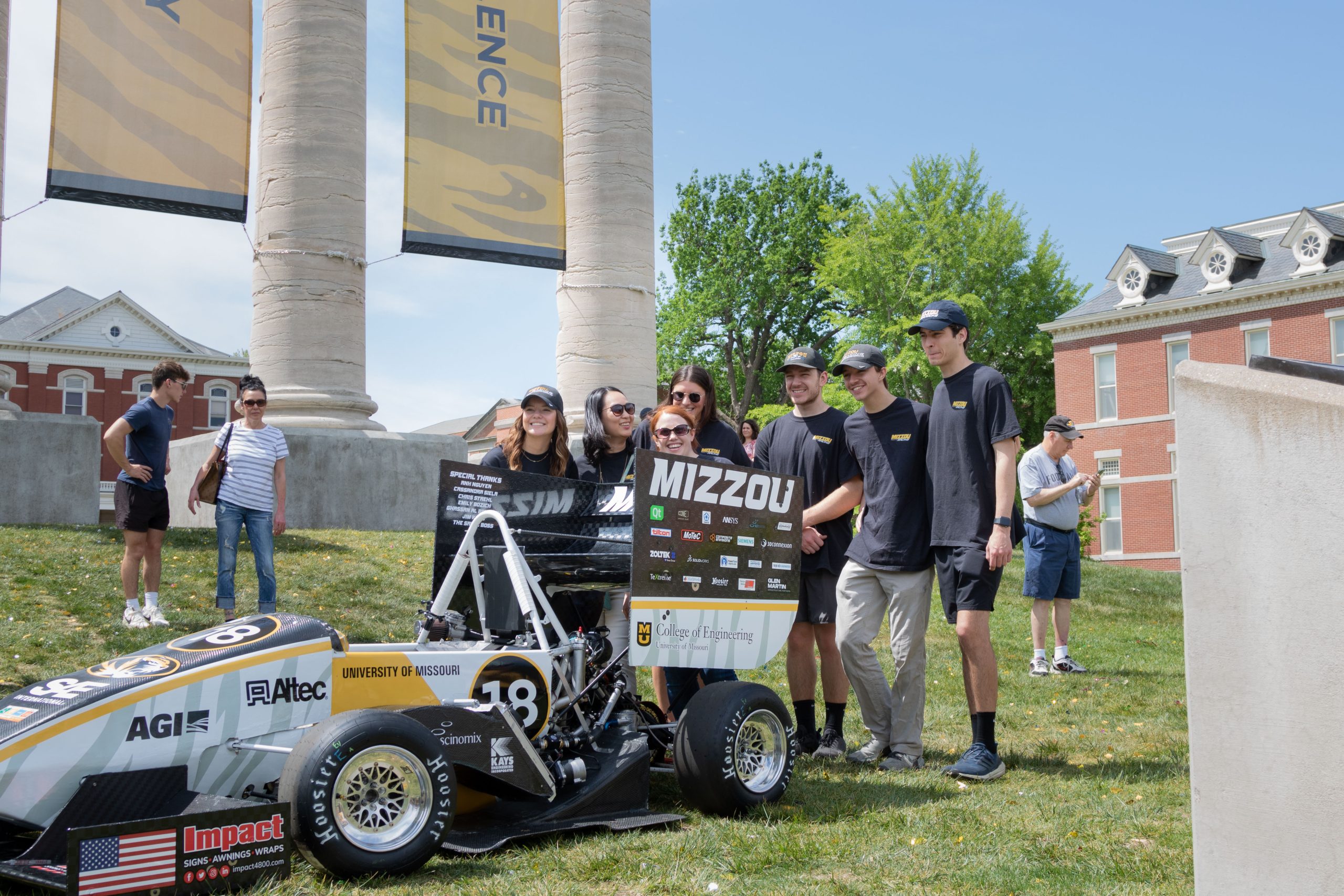 Formula SAE students stand next to their racecar. 