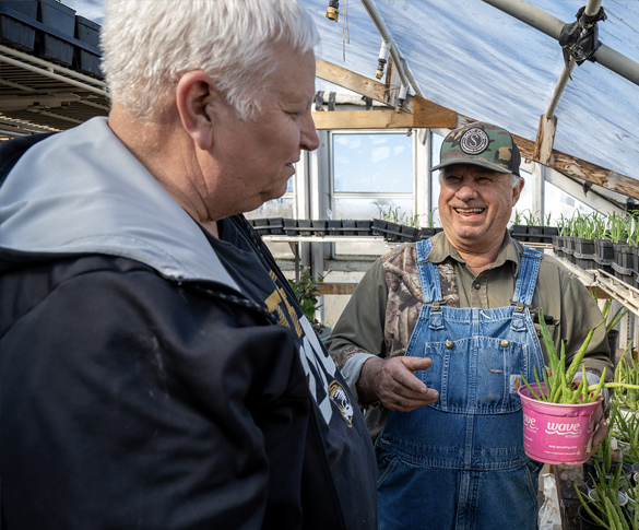 two men in a greenhouse smiling
