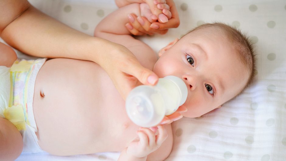 Mother feeding her child from a bottle. Breastfeeding vs bottle formula feeding. Motherâ€™s love and warmth.